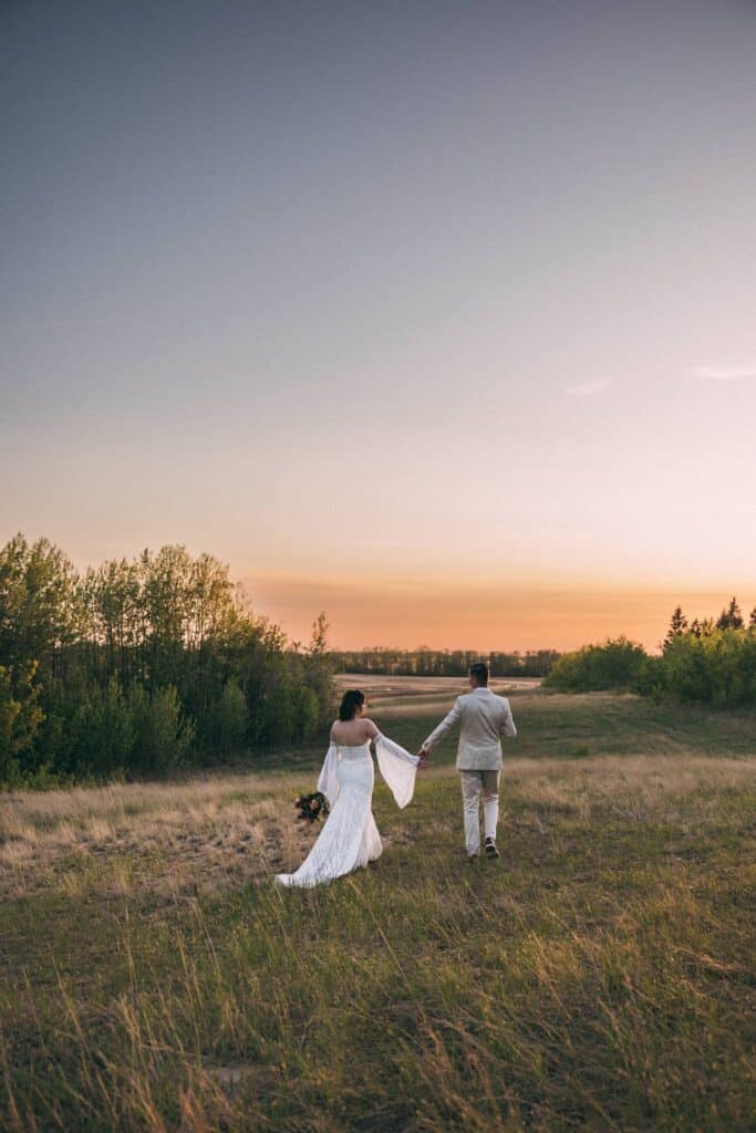 couple eloping at elk island retreat walking into the sunset