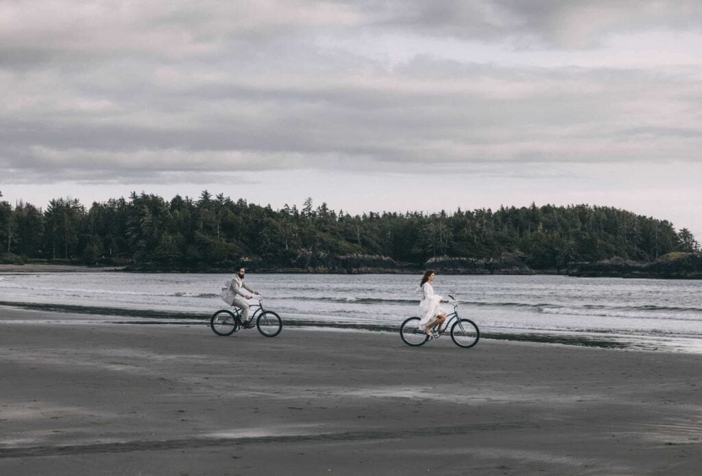 eloping in british columbia-  couple biking on the beach in tofino