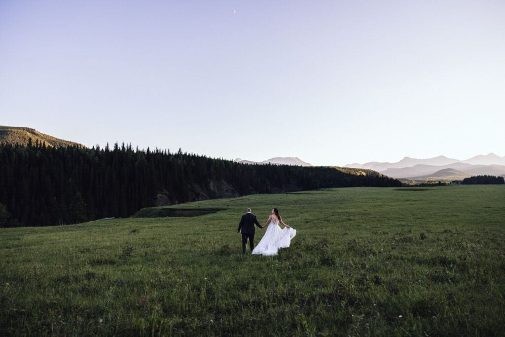 wedding couple running in the field in alberta canada by the kananaskis